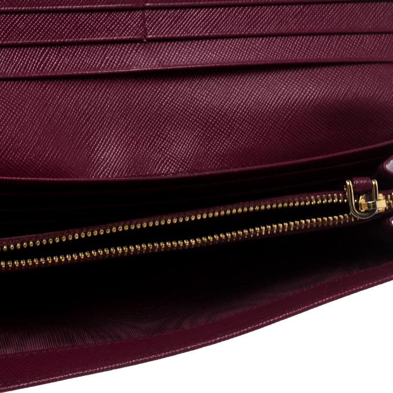 Crafted from Saffiano leather, this gorgeous continental wallet from Prada carries a feminine magenta exterior. The front flap is accented with gold-tone Prada lettering and opens to a leather and nylon interior equipped with multiple slots and a