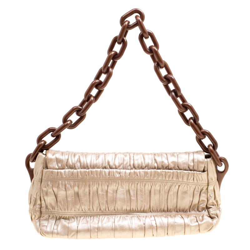 Gaufre shoulder bag from the house of Prada is designed in a metallic beige ruched leather with a 'Prada' embossed buckle closure. It features a giant chain shoulder strap and opens to a nylon-lined interior that can easily hold your essentials. A