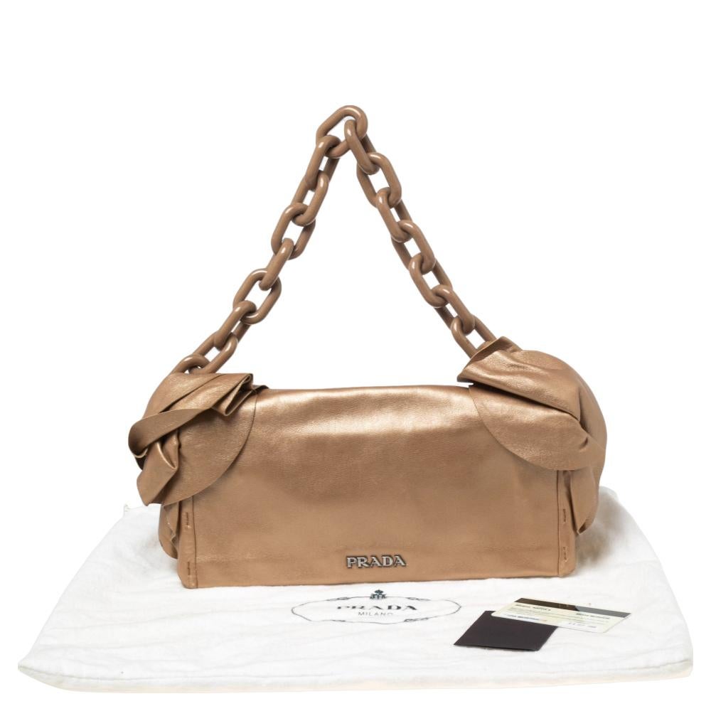 Channel your fondness for Prada with this leather bag that's beautified with ruffle trims. This pretty creation can hold more than just essentials in its nylon-lined interior. It is accompanied by a chain handle.

