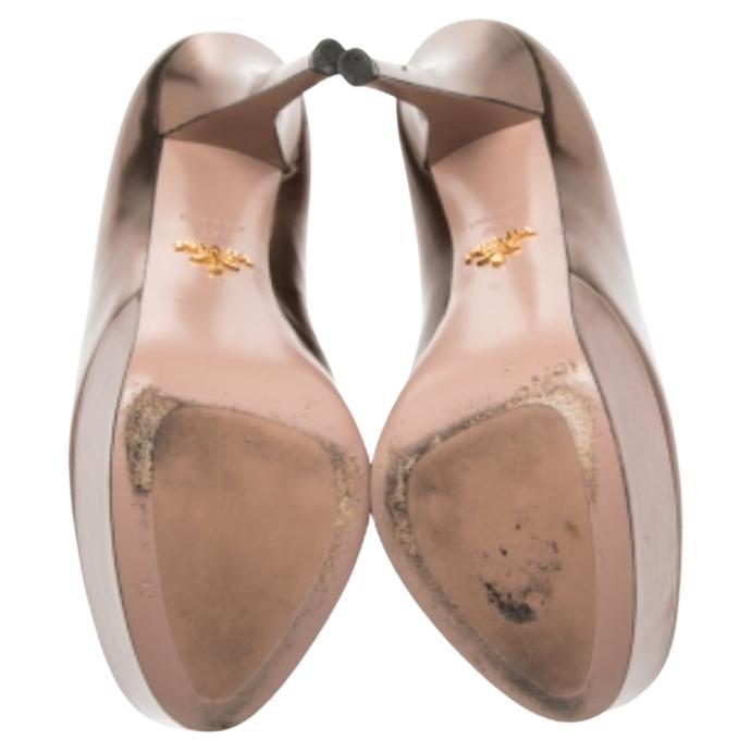 Transform into a style diva when you wear these lovely Prada pumps. They are crafted from metallic bronze leather and styled with round toes and well-cut vamps. They come equipped with comfortable leather-lined insoles, platforms, and 13 cm heels.