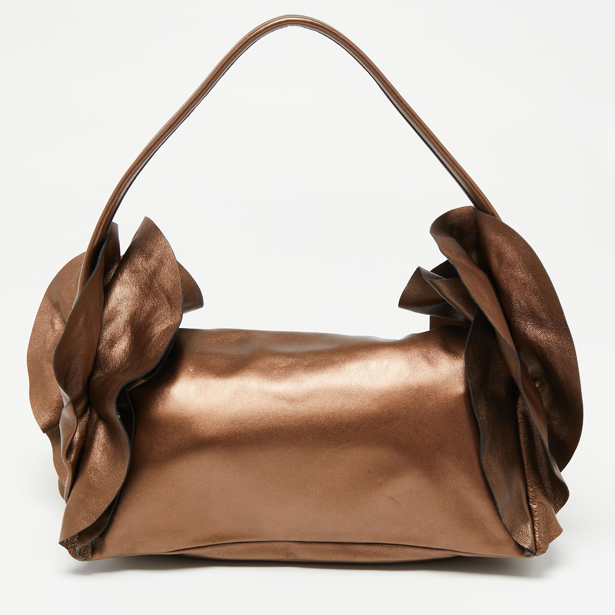 Attend those parties in style by carrying this stunning clutch from Prada. It has been designed in a lovely metallic bronze shade and is styled with ruffle trim details on the sides. It flaunts a silver-tone brand logo on the front and comes endowed