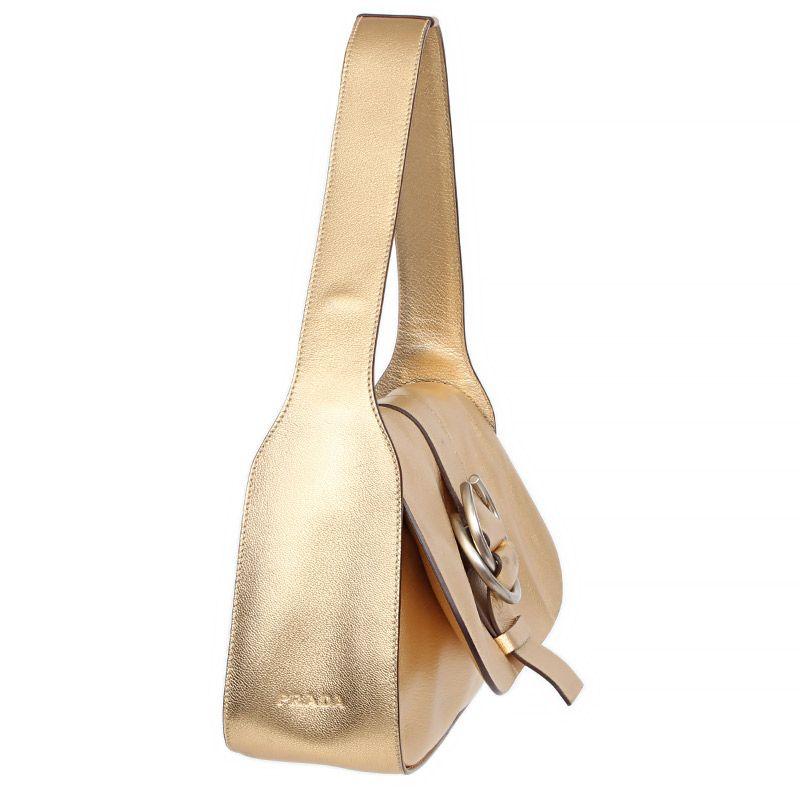 Prada shoulder bag in gold glazed leather with an outside button pocket on the back. Opens with a flap and concealed press-on button. Lined in espresso brown fabric. One zipper pocket against the back. Has been carried and shows overall signs of
