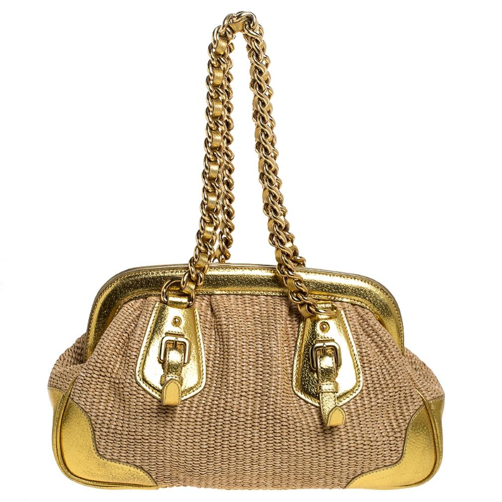 This stunning frame bag by Prada is a must-have. It is crafted in Italy and made of quality straw. It comes in a stunning shade of gold and adds a touch of glamour to every outfit. The exterior features leather trims and a brand logo. The bag opens