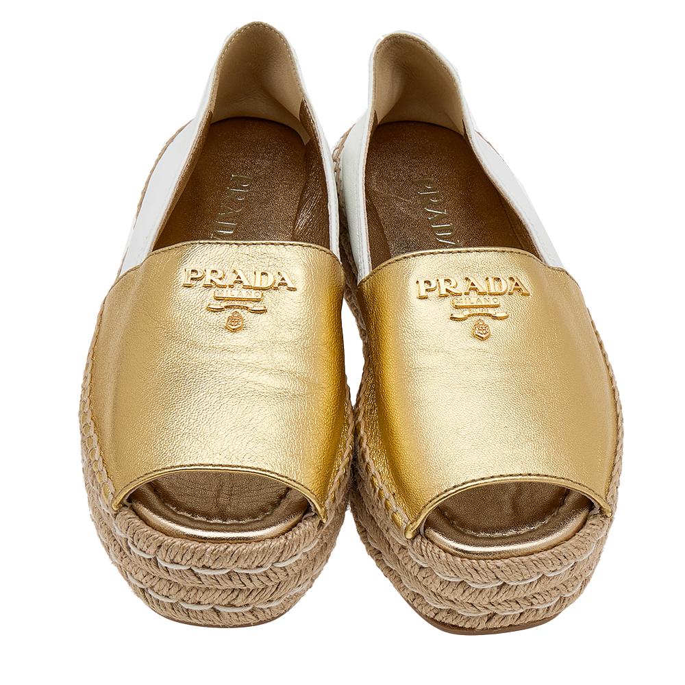 Let your feet feel stylish and comfortable at the same time as you wear these espadrille flats from Prada. The exterior of these flats is created using gold/white leather and has a peep-toe cut and brand logo on the uppers.

