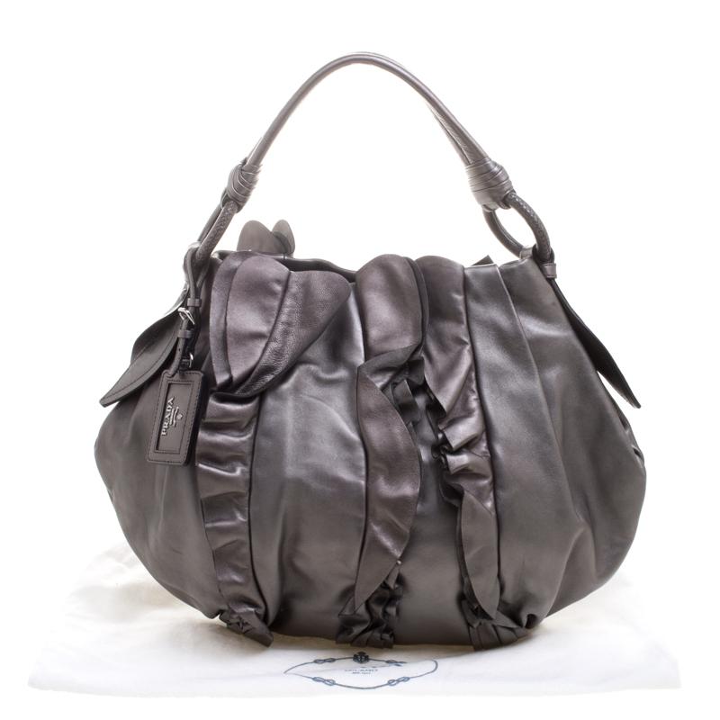 Prada brings to you this hobo that is an absolute delight. Gorgeous in a metallic grey shade, this hobo is crafted from leather and features an artistic ruffle detailing on the front and back. It flaunts a single handle with an attached tag accent