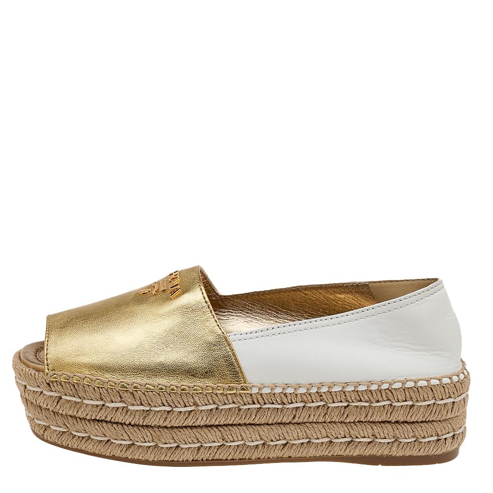 Let your feet feel stylish and comfortable at the same time as you wear these espadrille flats from Prada. The exterior of these flats is created using gold/white leather and has a peep-toe cut and brand logo on the uppers.
