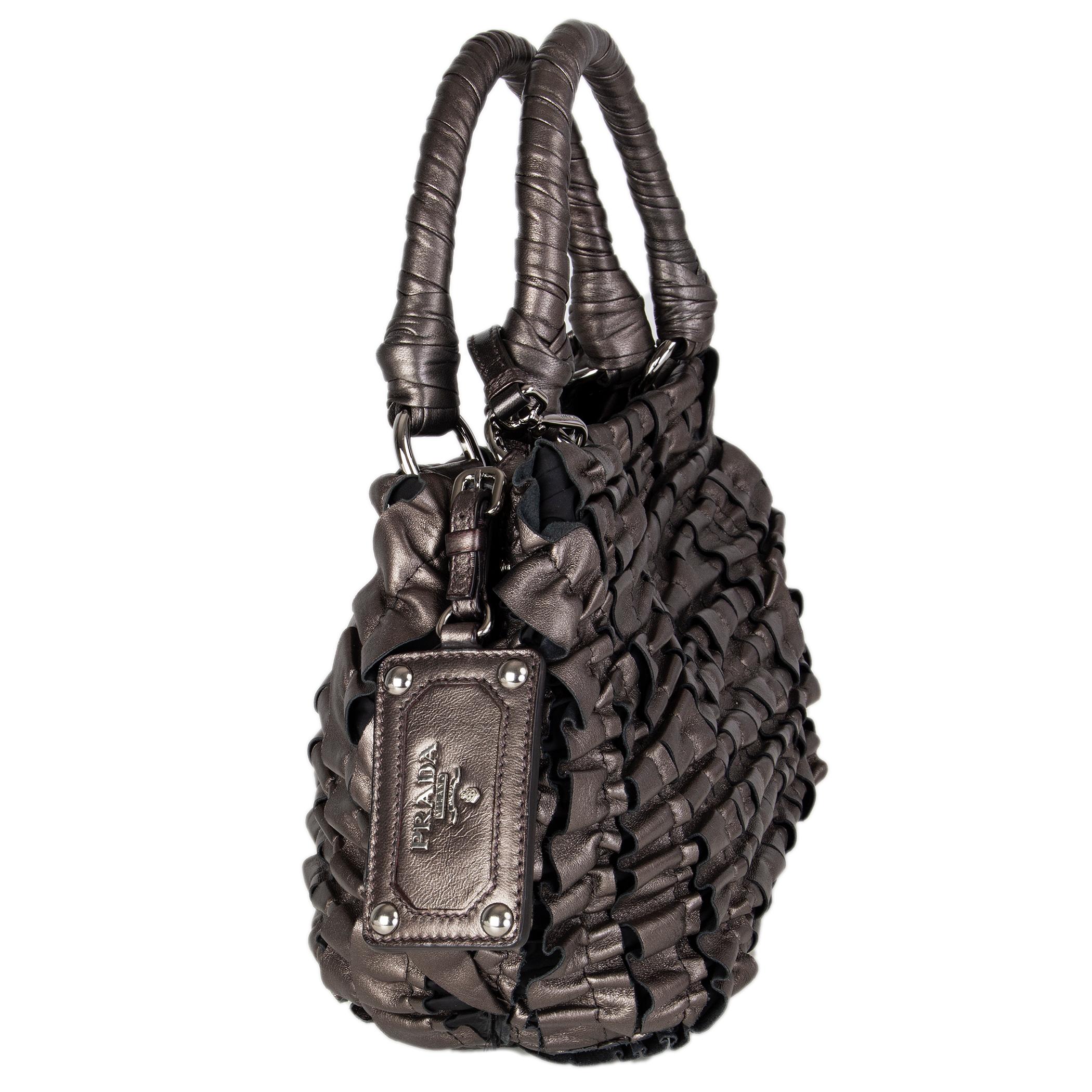 Prada ruched small shoulder bag in metallic pewter leather. Detachable and adjustable shoulder strap. Closes with a magnetic-snap on top. Lined in black monogram nylon with an open pocket against the front and a zipper pocket against the back. Has