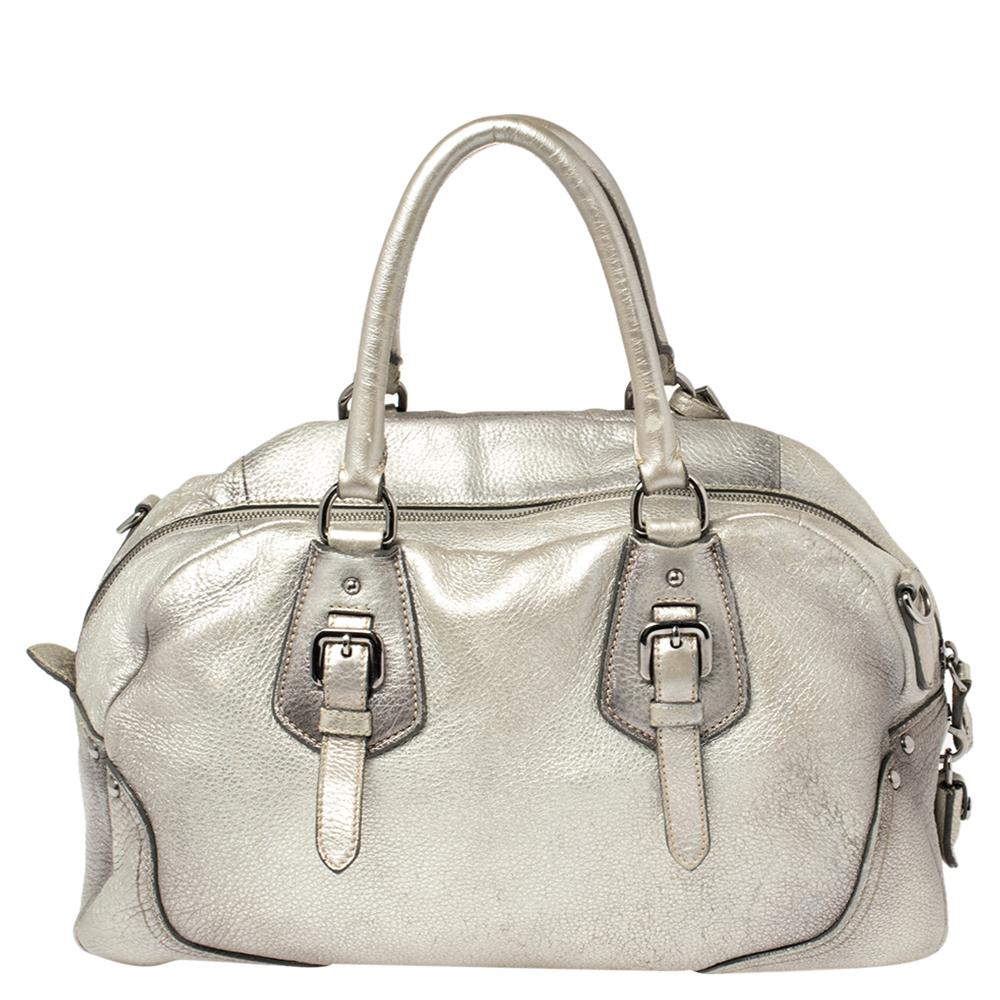 This lovely bag from Prada is crafted from metallic silver leather. It flaunts dual top handles, a brand logo on the front, buckle details, and a nylon-lined interior with enough space to house all your belongings. It is finished with silver-tone