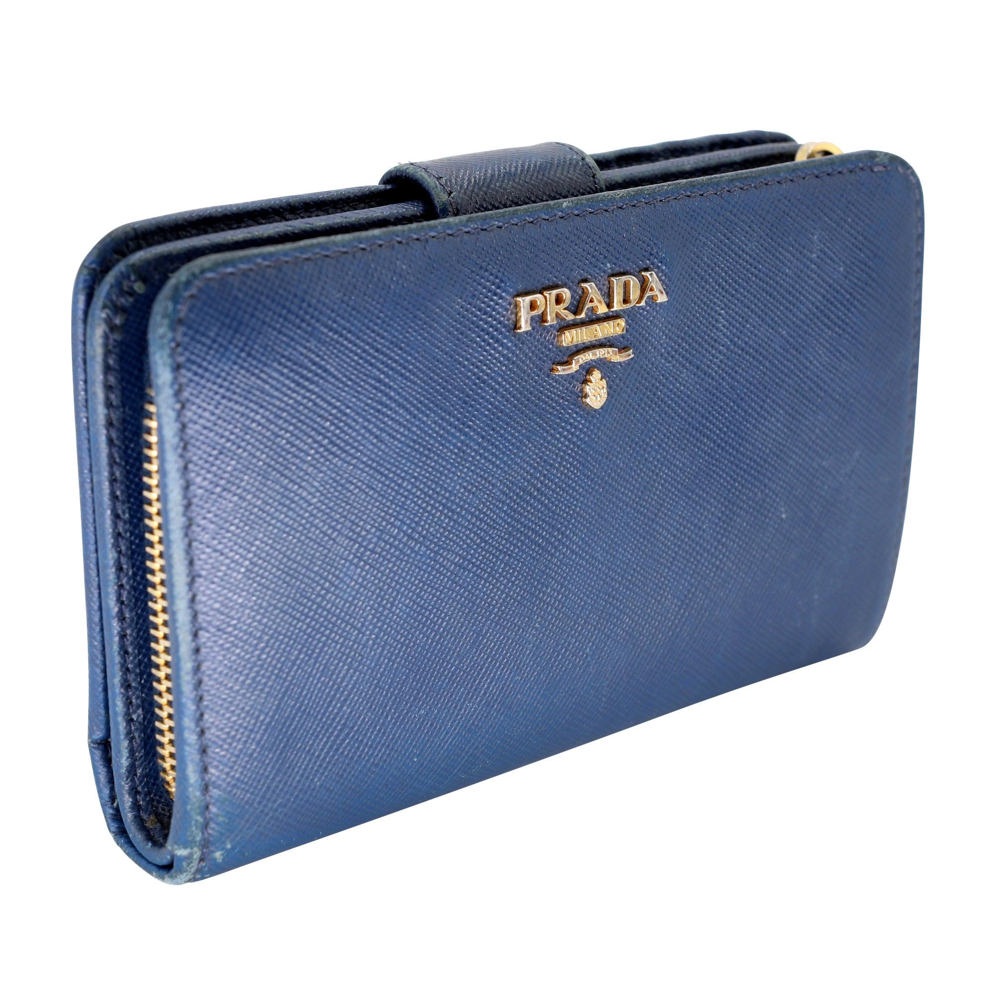 This cute and sophisticated small Prada Saffiano wallet features a durable Saffiano leather and gold-tone hardware accents with a button lock closure. It will hold all your credit cards as well as your on-the-go coins and more. The exterior leather