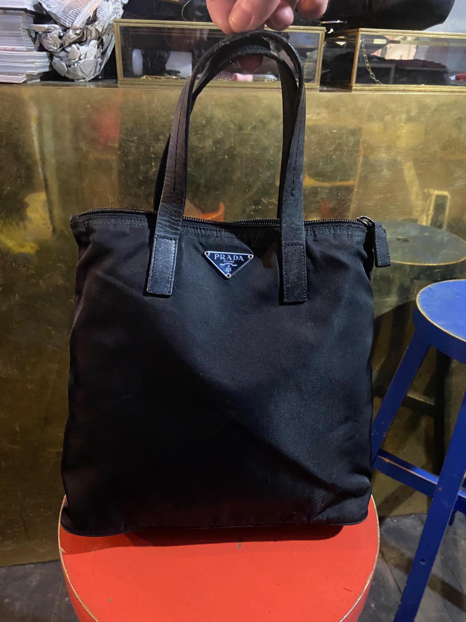 Vintage Mini Prada Tote Bag Features Acrylic outer layer. Black leather handle, Zip on the top and inside pocket. Prada Logo in metal on front of bag. In excellent vintage condition. 

Brand: Prada
Color: Black
Fabric: Canvas/Leather
Year / Season :
