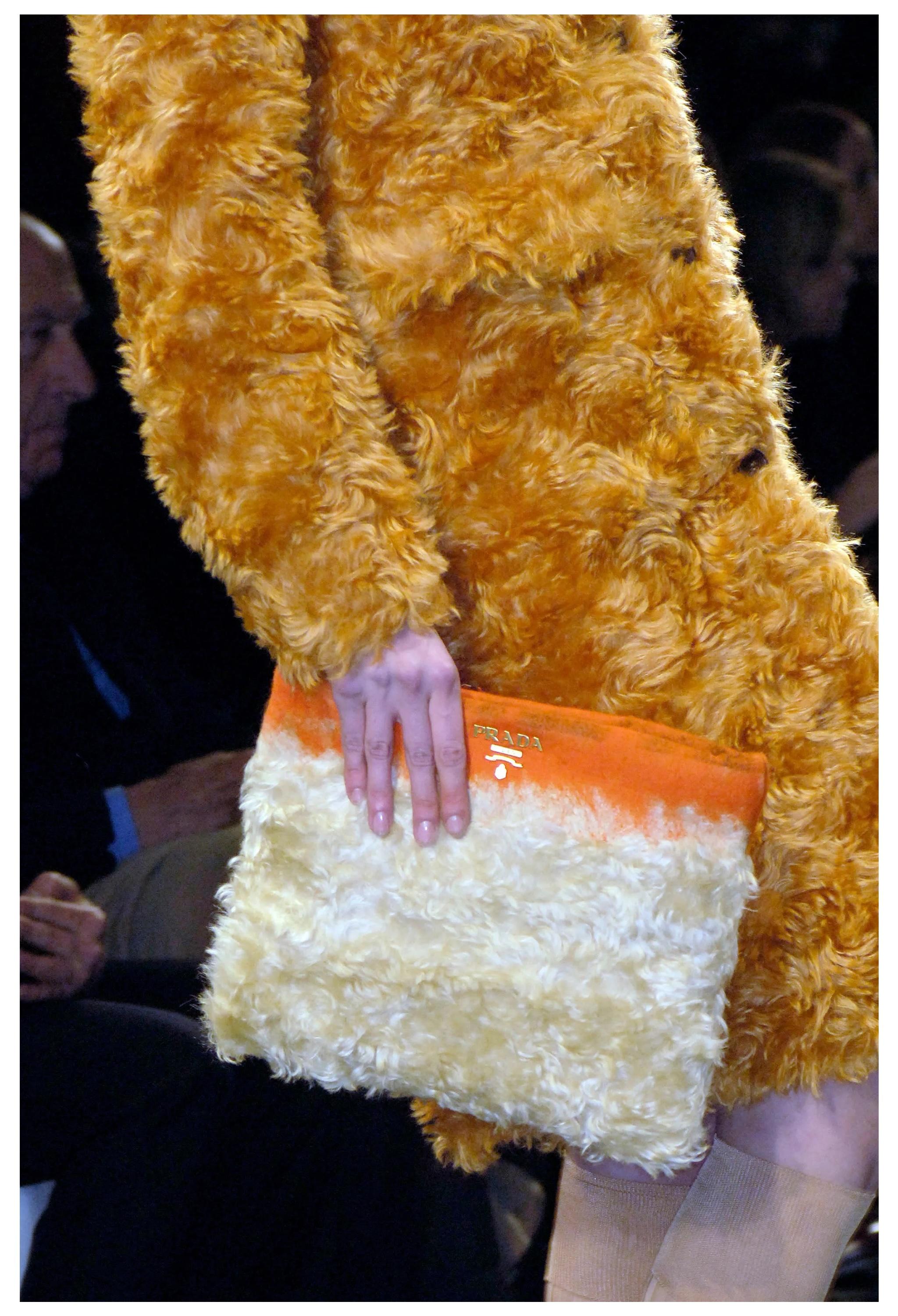 Resurrection Vintage is excited to offer a vintage Prada orange mohair clutch from the 2007 runway collection. This bag features a mix of orange wool and beige mohair, gold-tone Prada hardware on the front, top zip closure, and black nylon Prada