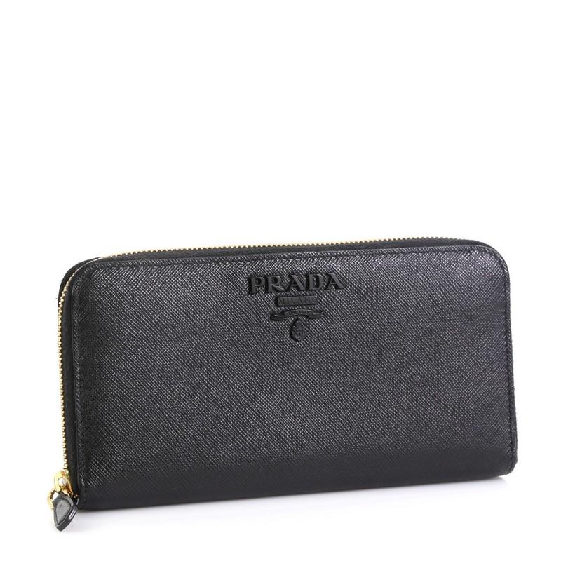 This Prada Monochrome Zip Around Wallet Saffiano Leather, crafted from black saffiano leather, features gold-tone hardware. Its zip closure opens to a black leather interior with multiple card slots and zip pocket. 

Estimated Retail Price: