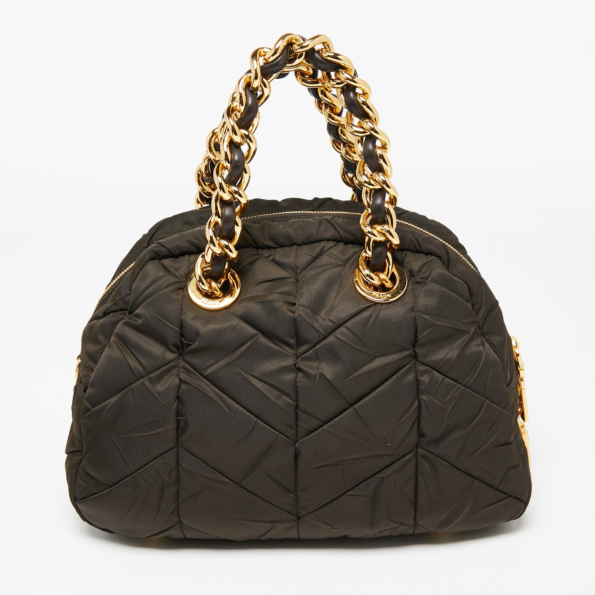 Stunning in appeal and high on style, this satchel from Prada is a must-have accessory! It is created using moss-green quilted nylon. It exhibits dual chain-embellished handles, gold-tone hardware, and a roomy nylon-lined interior. Elevate your