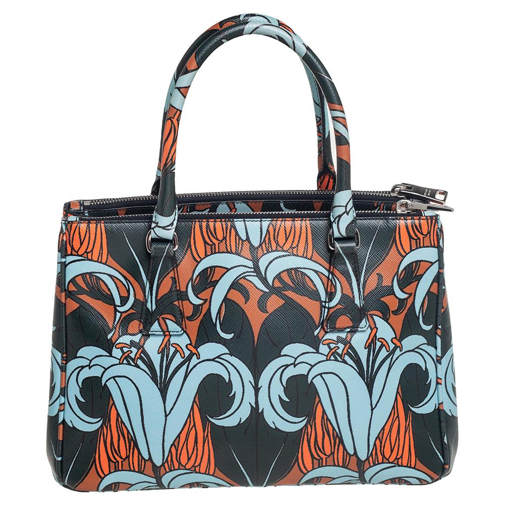 Loved for its classic appeal and functional design, Galleria is one of the most iconic and popular bags from the house of Prada. This multicolored beauty is crafted from lily printed Saffiano leather and is equipped with two top handles, the brand