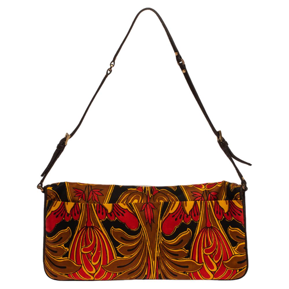 Designed in a pochette silhouette, this bag by Prada is a marvelous creation. Crafted with silk, the exterior of the bag is delicately designed with a tulip print all over. The front flap opens to an ideally sized satin interior. Complete with a