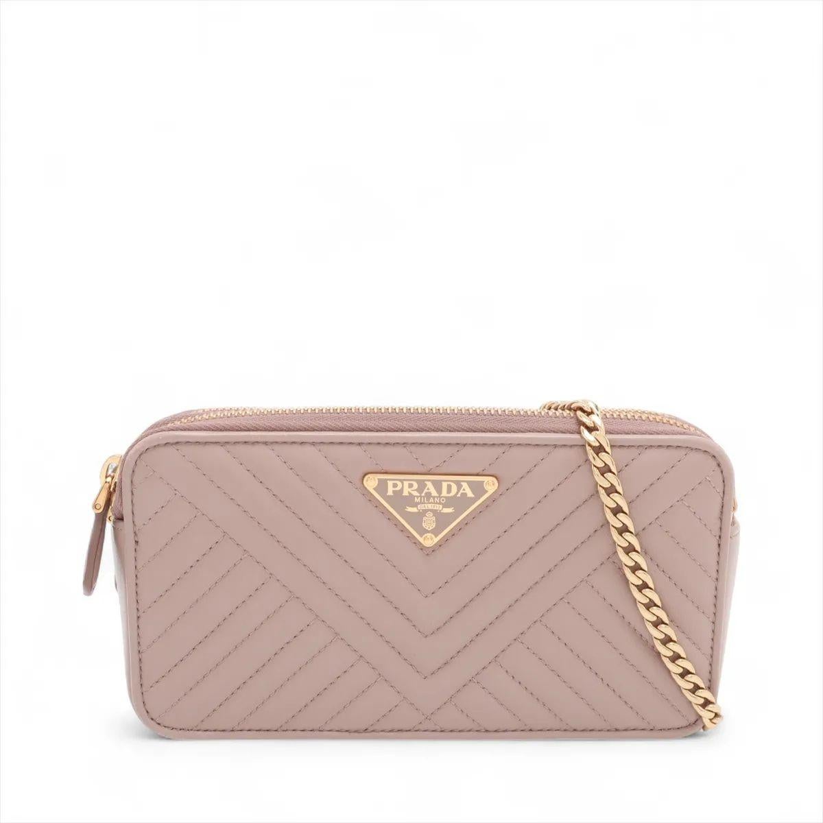 Die Prada Nappa Impuntu Leather Chain Wallet in Rosabeige ist ein raffiniertes Accessoire, das die moderne Eleganz und Handwerkskunst der Marke unterstreicht. Sie ist aus weichem Nappaleder mit einem unverwechselbaren Steppmuster gefertigt und