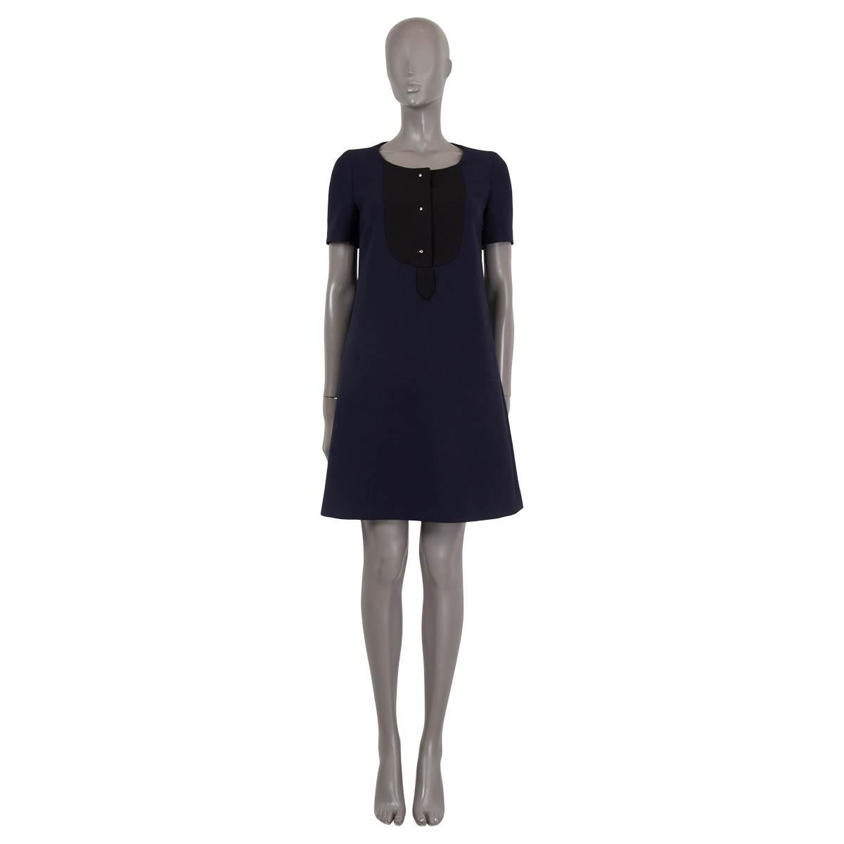 100% authentic Prada short sleeve A-line dress in navy wool (100%). Features a black plastron with three silver buttons and two pockets on the side. Opens with a zipper on the side. Lined in viscose (67%) and silk (33%). Has been worn and is in