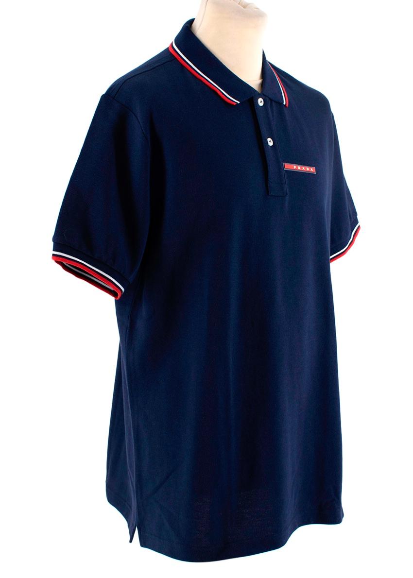 Prada Marineblau Baumwolle Pique Kontrast Trim Poloshirt
 

 - Marineblaues Kurzarm-Poloshirt aus Piqué-Baumwolle
 - Rot-weiße Zierleiste am gespreizten Kragen und an den Manschetten
 - Rotes Prada-Logo mit Balken auf der Brust
 -