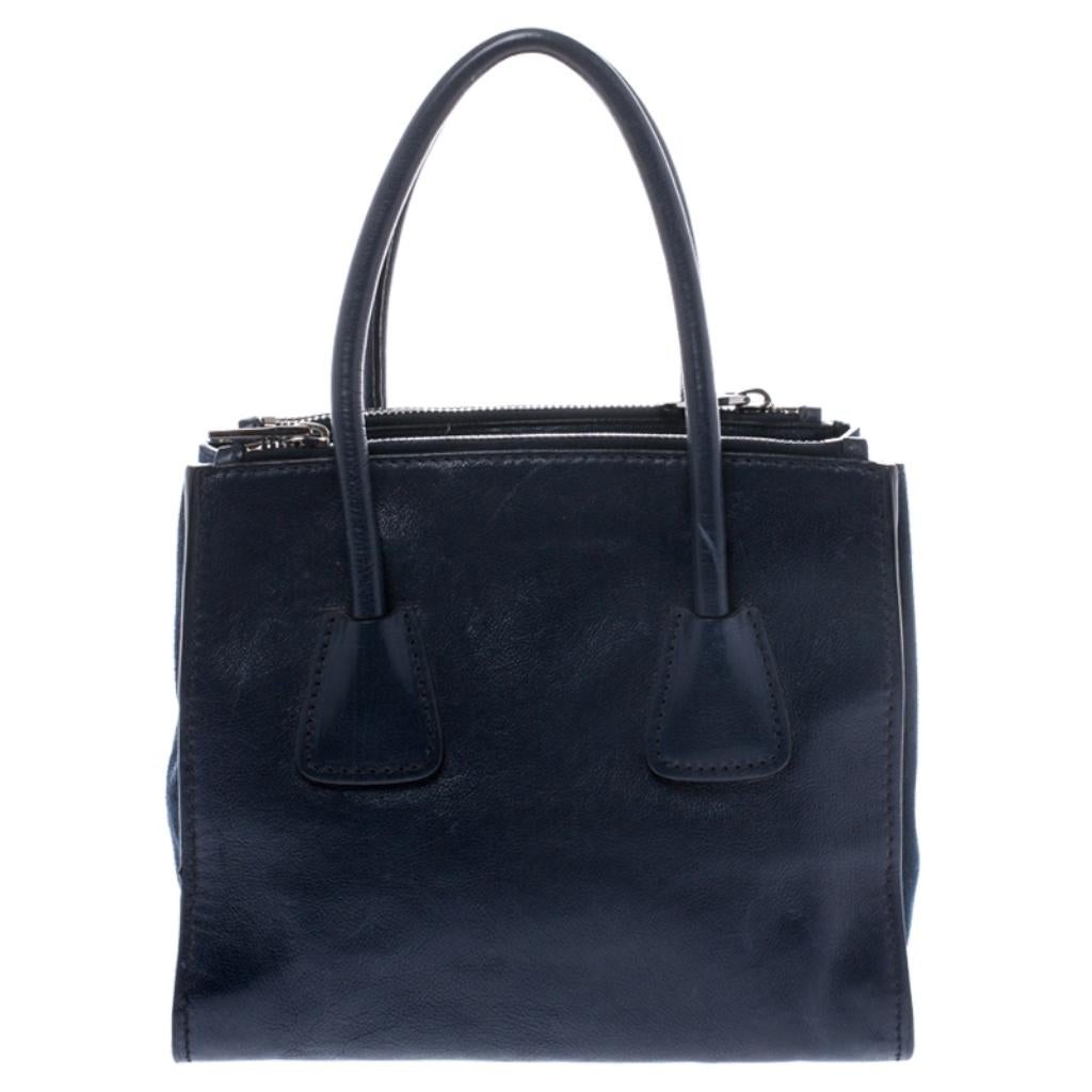 Add some effortless style and luxury to your everyday looks with this stunning Prada tote. Crafted in navy blue leather and suede, this bag can store all that you need in its large interior. The bag is equipped with the brand logo on the front, dual