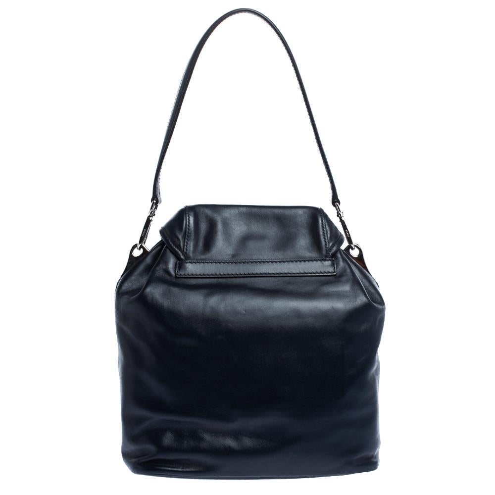 This lovely shoulder bag by Prada is stylish and functional. It has a leather exterior and carries a classic shade of navy blue. It is styled with a single handle, double pockets on the front, a spacious nylon-lined interior and silver-tone hardware
