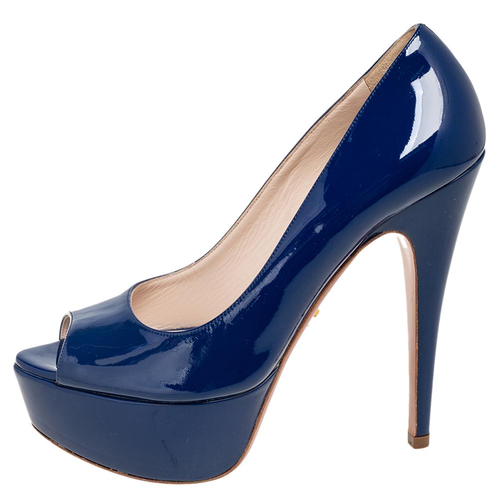 There are some shoes that stand the test of time and fashion cycles, these timeless Prada pumps are the one. Crafted from patent leather in a navy blue shade, they are designed with sleek cuts, peep-toes, and tall heels supported by