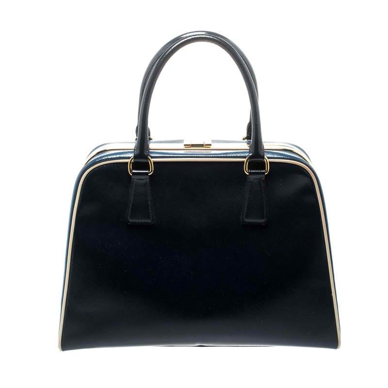 Stunning in appeal and high on style, this top handle bag by Prada will be a valuable addition to your closet. It has been crafted from patent leather and styled minimally with gold-tone hardware. It comes with dual top handles, protective metal