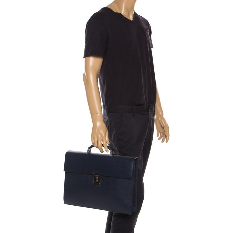 This Prada briefcase brings such a fantastic shape that you're sure to look fashionable whenever you carry it. It has been crafted from Saffiano Cuir leather and designed with a top handle and a flap with a combination lock to secure the well-sized
