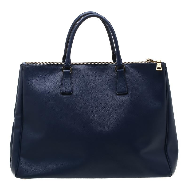 h Feminine in shape and grand on design, this Double Zip tote by Prada will be a loved addition to your closet. It has been crafted from leather and styled minimally with gold-tone hardware. It comes with two top handles, two zip compartments and a