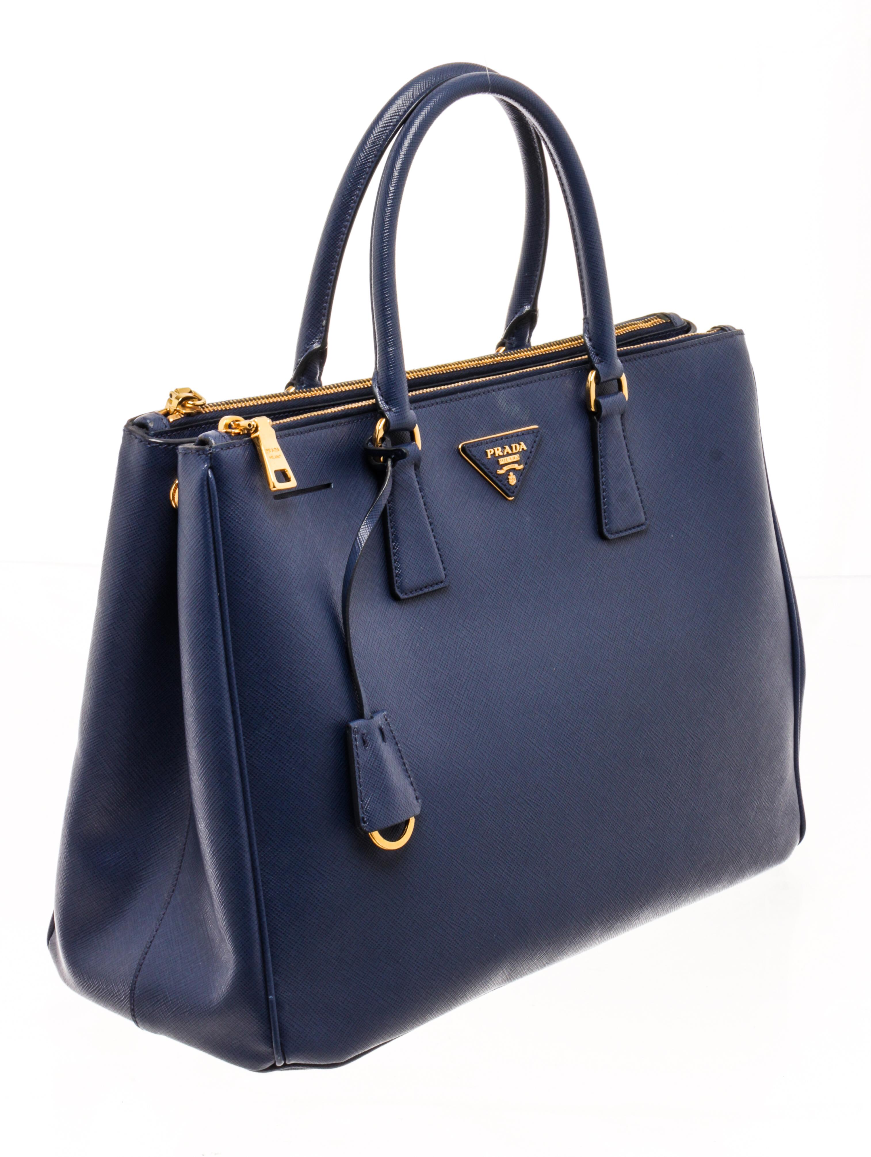 Prada Navy Blue Saffiano Leather Large Galleria Double Zip Tote Bag with this beauty in navy blue is crafted from saffiano leather and is equipped with two top handles, the brand logo on the front, and gold-tone hardware.

86774MSC