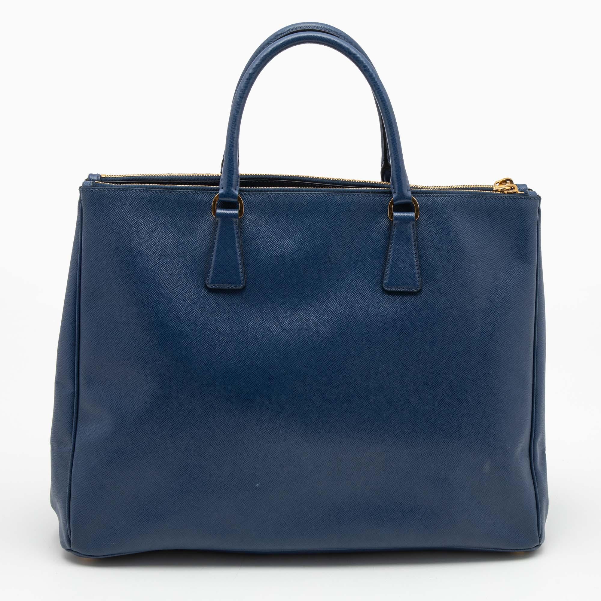 Loved for its classic appeal and functional design, Galleria is one of the most iconic and popular bags from the house of Prada. This beauty in navy blue is crafted from Saffiano lux leather and is equipped with two top handles, the brand logo at