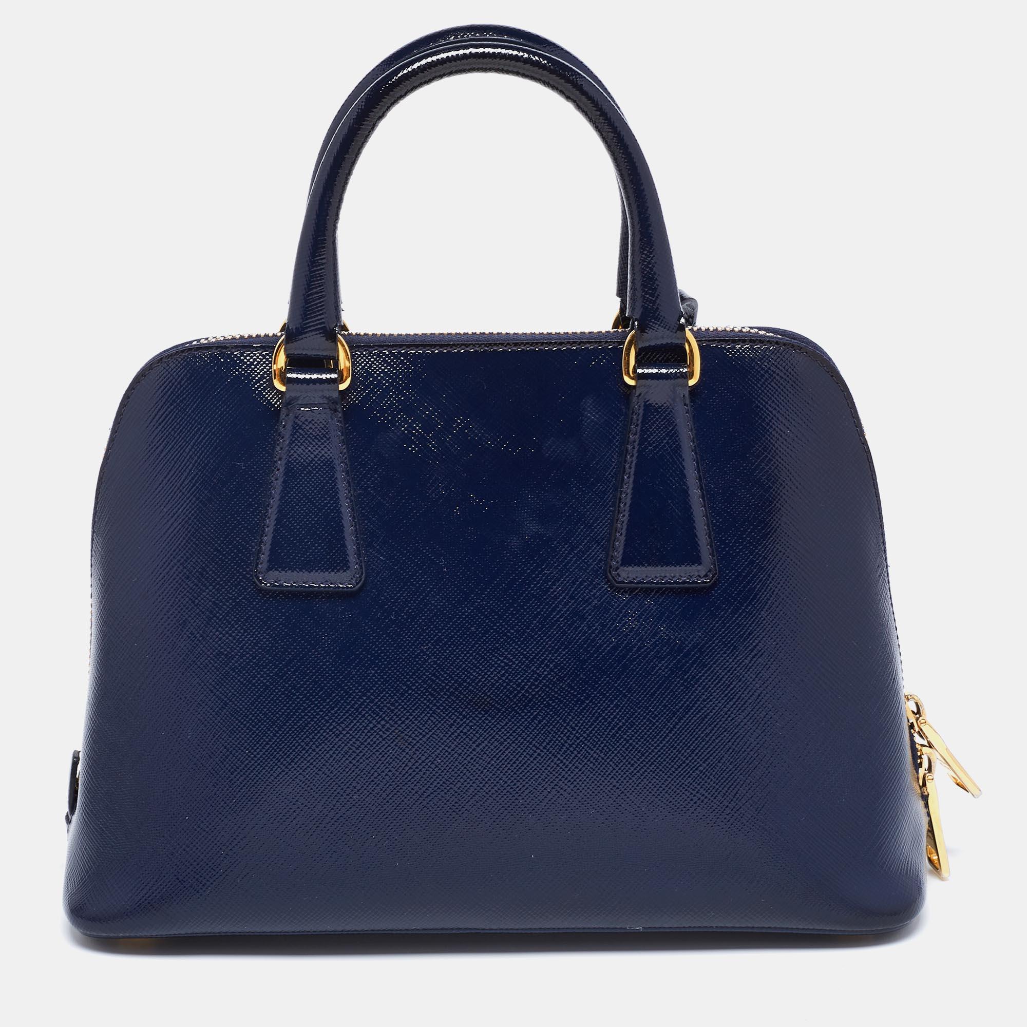 This stunning Promenade tote is high on appeal and style. Dazzling in a classy navy blue shade, the bag is crafted from Saffiano patent leather and features two rolled handles. The zip closure leads way to a nylon interior with enough space for your