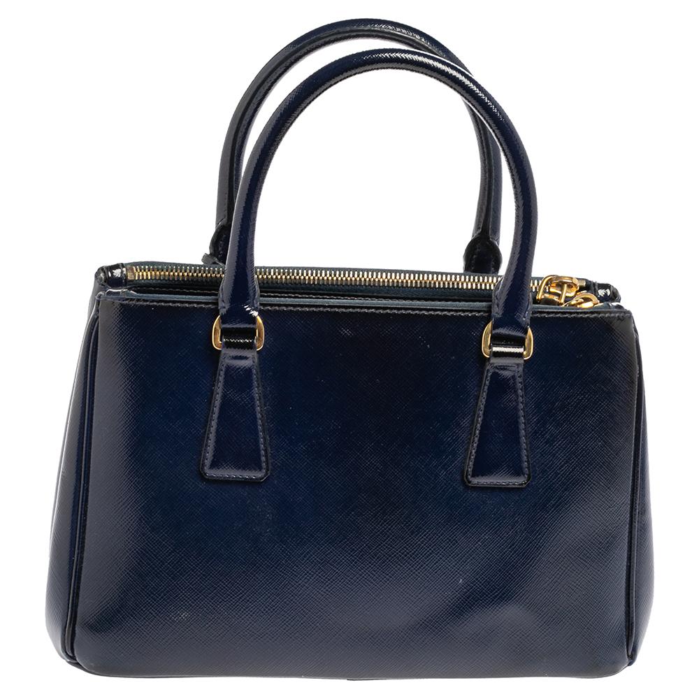 Feminine in shape and design, this Galleria Double Zip tote by Prada will be a loved addition to your closet. It has been crafted using Saffiano Vernice leather and styled minimally with gold-tone hardware. It comes with two top handles,