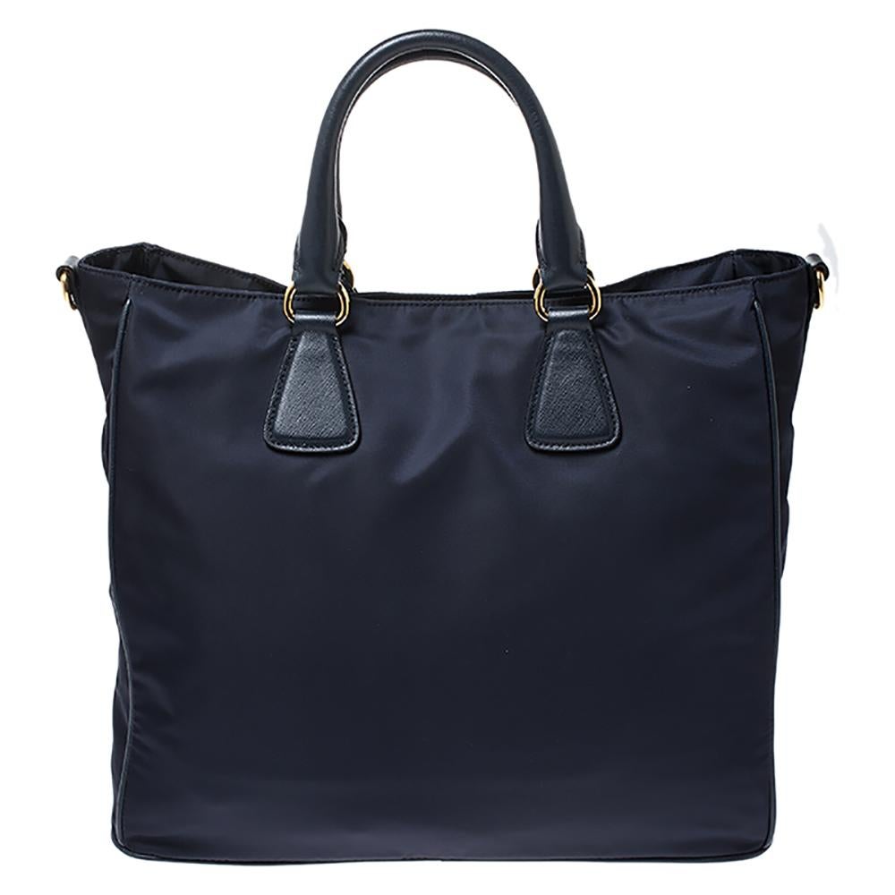 This outstanding tote bag by Prada will go well with almost all your outfits. Crafted from quality nylon and leather, it comes in a lovely navy blue hue. It is styled with dual handles, a brand tag, a brand logo, shoulder strap and a zip closure
