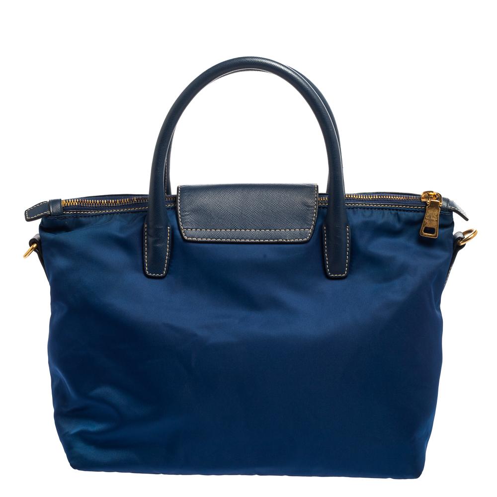 This Prada Tessuto tote is ideal for casual days spent out and about. Its lightweight nylon exterior is simply accented with Prada's iconic logo and gold hardware. It comes with rolled top leather handles, a small flap, and a leather strap. The