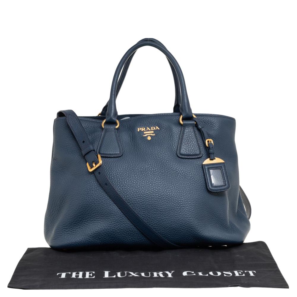 This Prada tote is finely crafted using Vitello Daino leather and fitted with dual top handles. It can be hand-held or used cross-body by attaching the shoulder strap. It has a spacious lined interior and the brand logo at the front.

Includes: