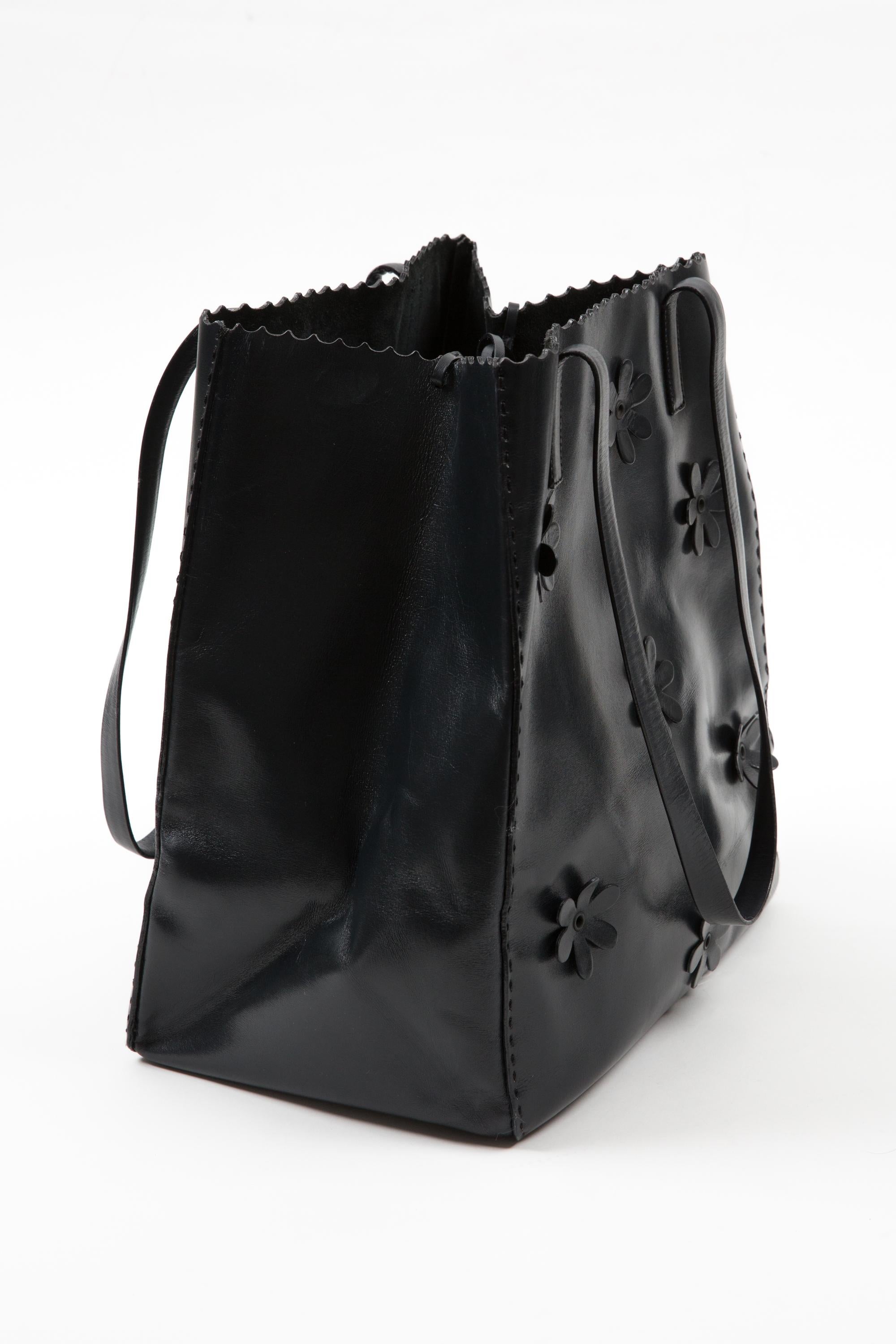 Prada neavy leather handbag featuring floral appliqué detailing, top tie closure, suede leather lining with inner pouch, side logo pitted, inside the enameled metal plaque. 
Circa 2010s. 100% Leather
In good vintage condition. Made in Italy.
Length: