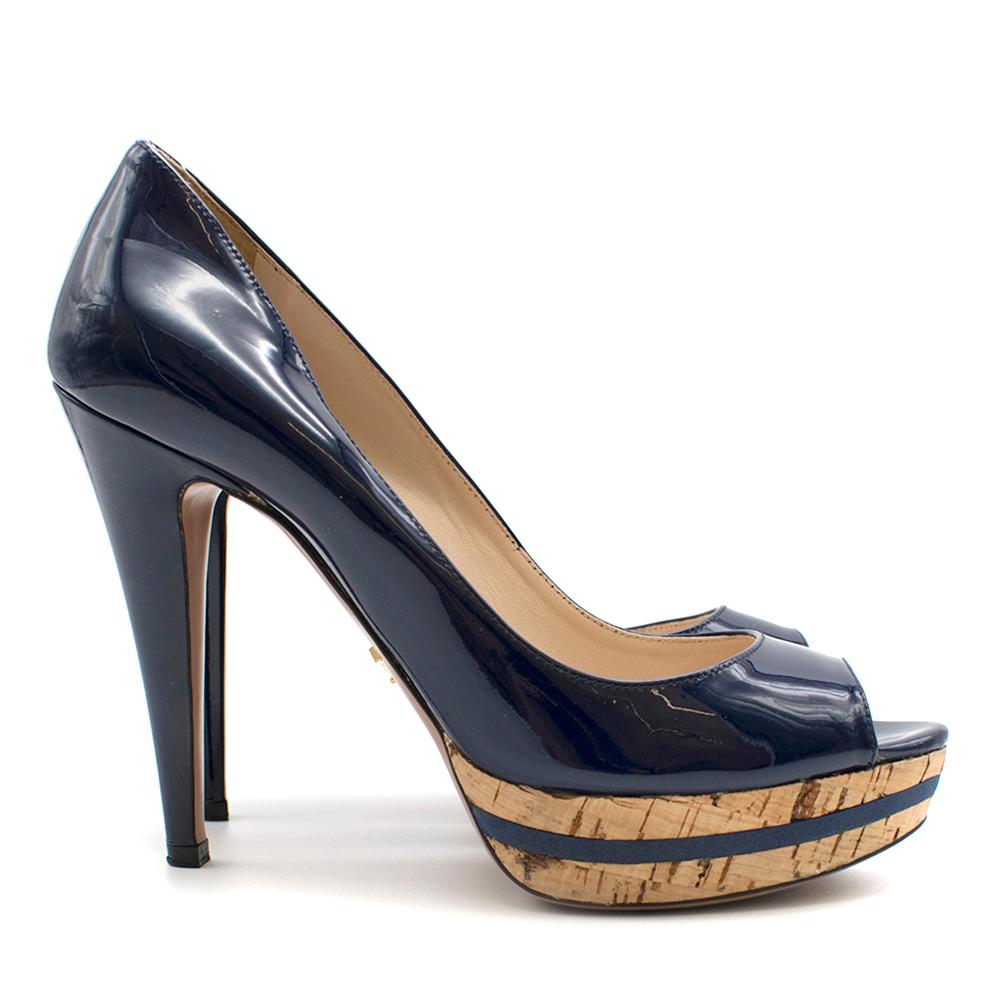 Prada Open-Toe Platform Pump

Prada cork platform 
Navy blue patent leather 
Open-toe pumps
Blue line around cork
Cream insole 
Beige sole with gold Prada logo 
Slip on
Dust bag included

Please note, these items are pre-owned and may show signs of