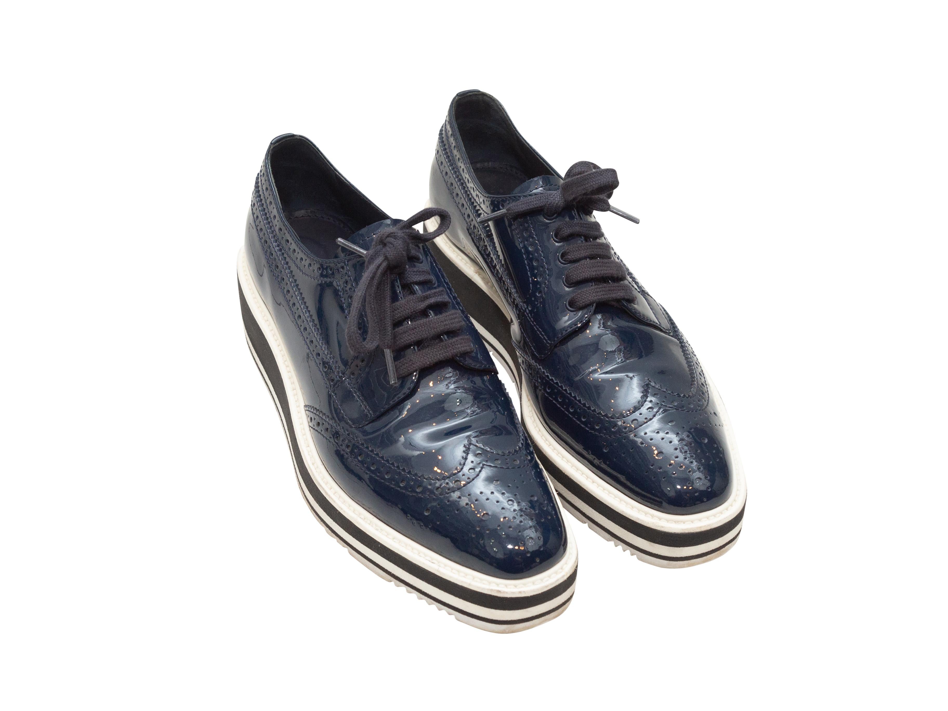 Product details: Navy patent leather platform brogues by Prada. Foam rubber soles. Lace-up tie closures at tops. Designer size 38.5. 1.75