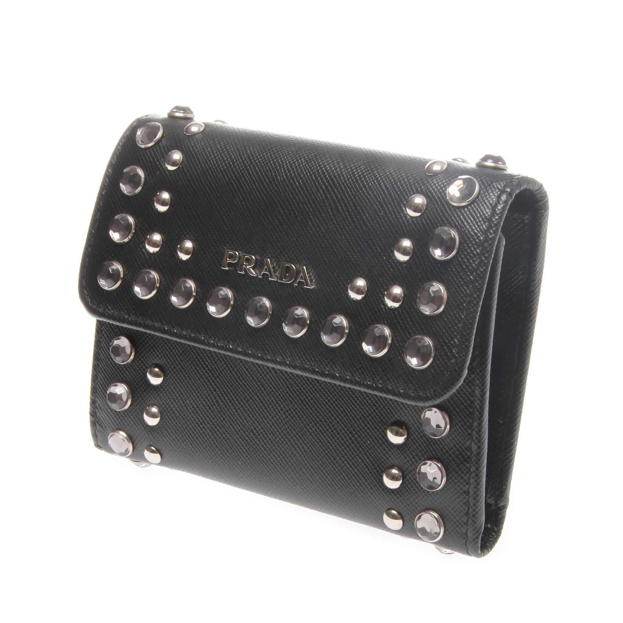 Prada navy saffiano tri-fold wallet embellished with clear crystals and silver tone metal studs. Featuring push stud closure at front flap, card slots, push stud coin compartment and a bill section. 

Original box 