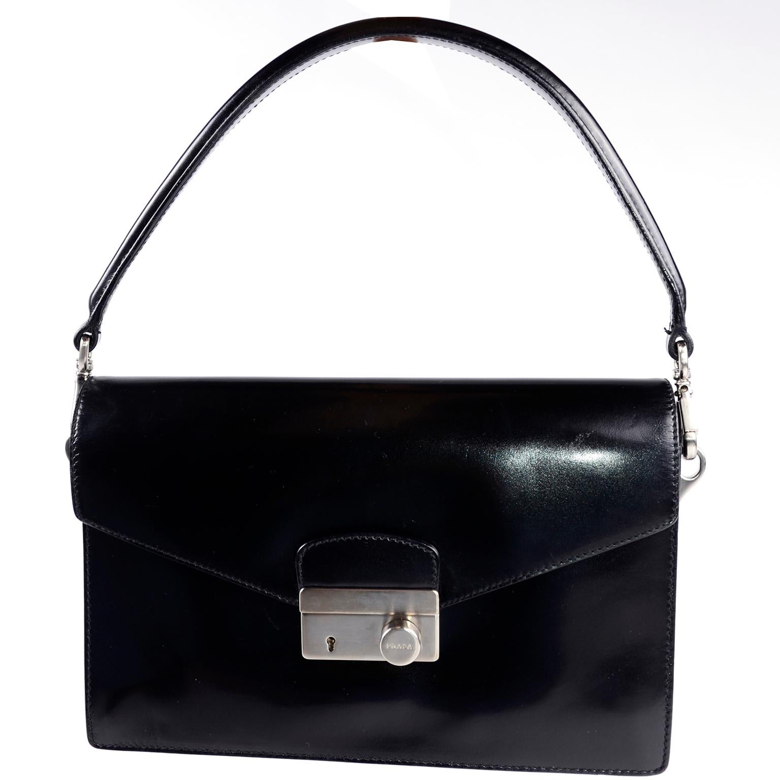 This 1990's Prada Black Leather Vitello Sound flap handbag has a removable top handle and it comes with its original dust bag. We love the green leather lining! The structured bag has an interior fixed 