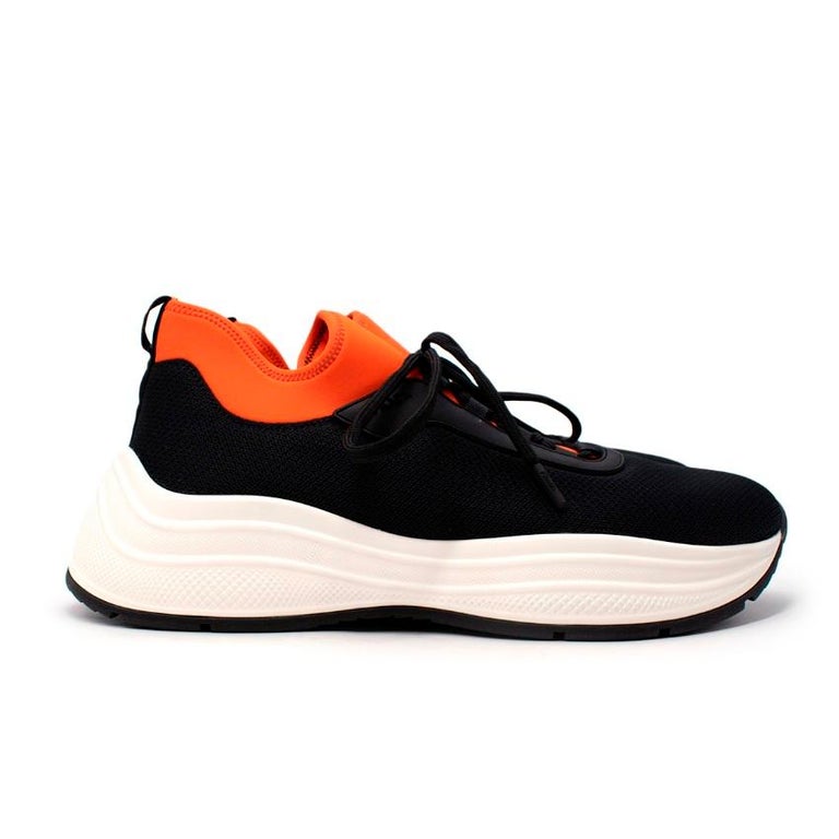 Prada New America's Cup Sneakers
 

 - Black mesh, sock-style body with orange neoprene ankle
 - White rubber formed sole
 - Lace-up front 
 - Logo on tongue 
 

 Materials
 100% polyester 
 61% nylon
 24% polyurethane
 15% elastane
 

 Made in
