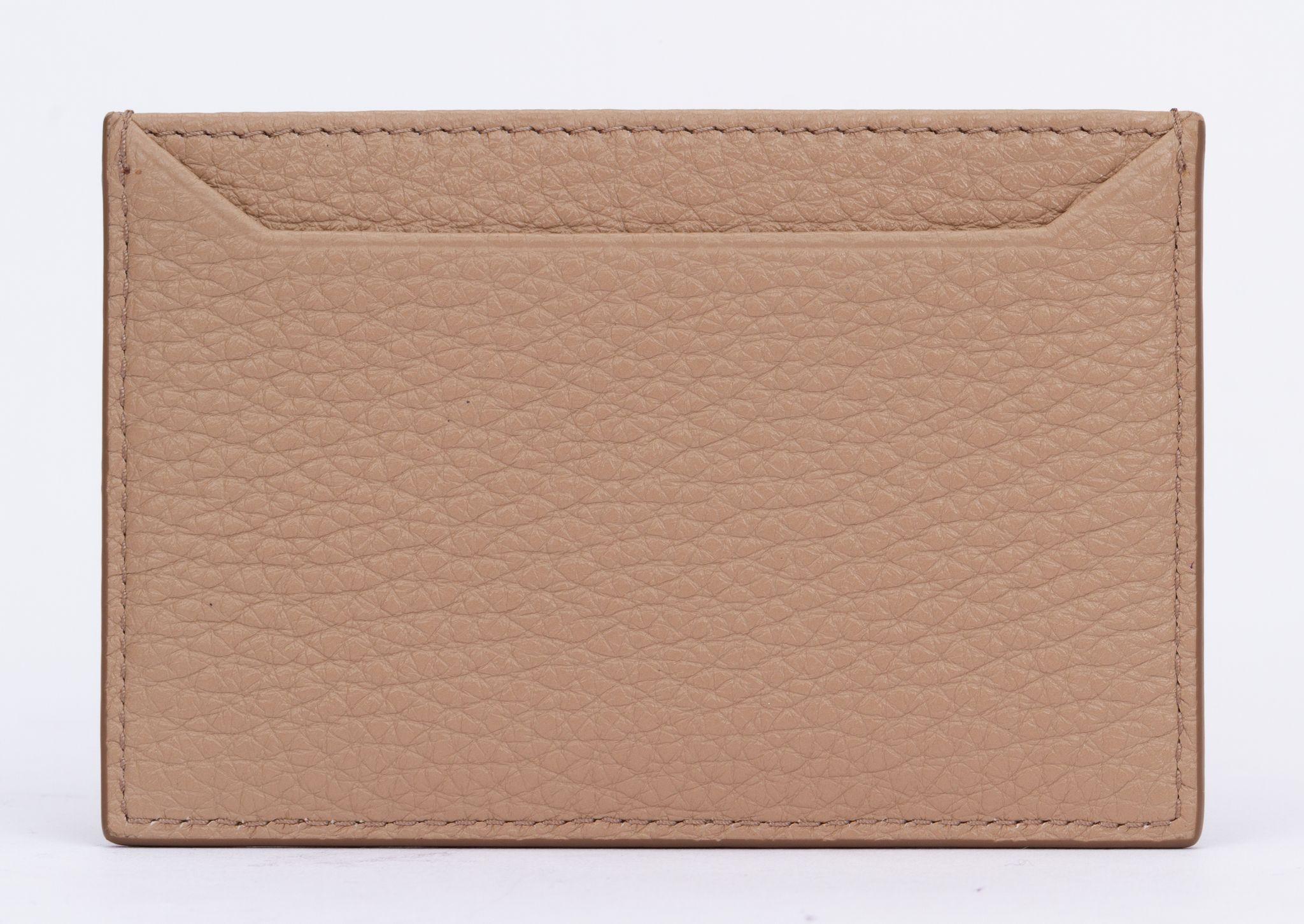 Prada Card Holder in Beige. This slim, stylish calf leather credit card holder offers three compartments with a contrasting color lining. Its chic gold-finish hardware pairs with a metal lettering logo to finish. It is brand new and comes with the