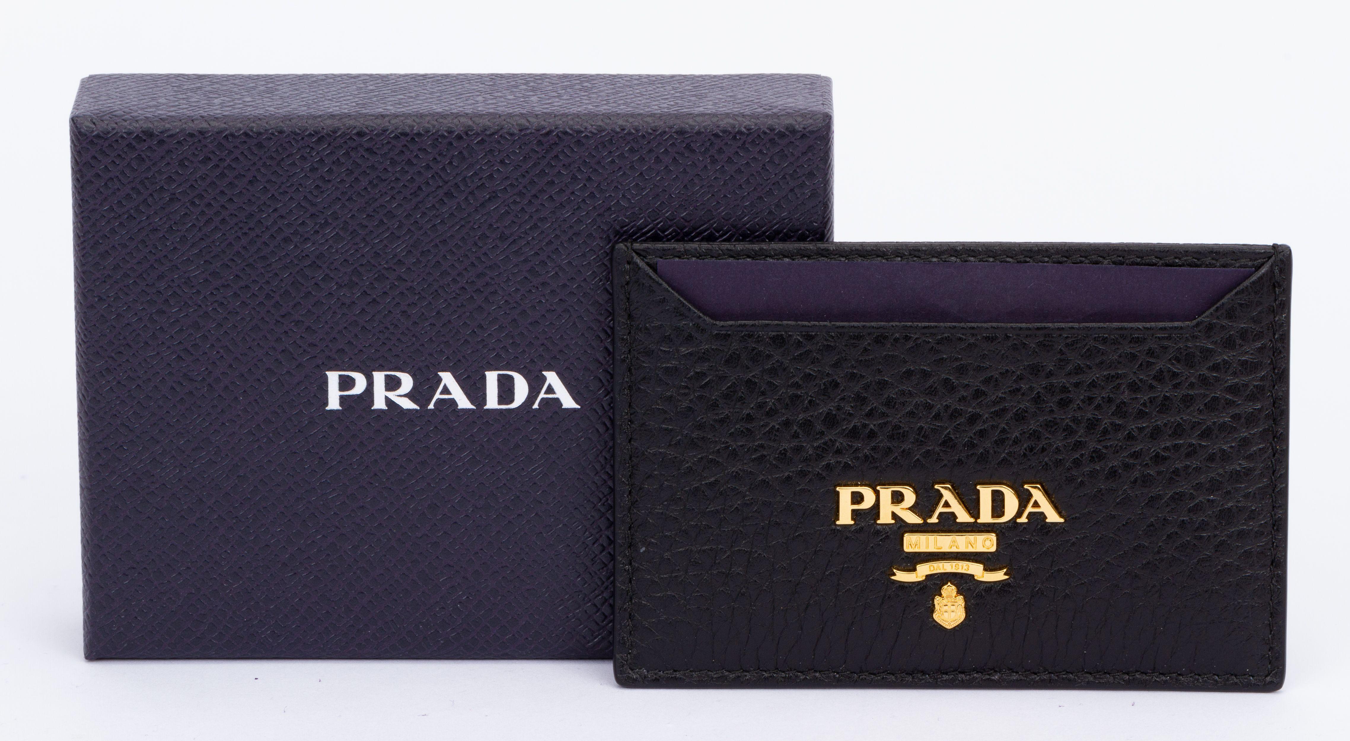 Prada card holder in black This slim, stylish calf leather credit card holder offers three compartments with a contrasting color lining. Its chic gold-finish hardware pairs with a metal lettering logo to finish. The piece is brand new and includes