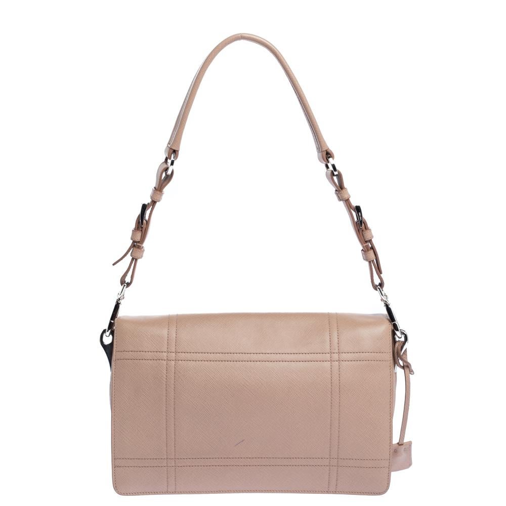 Prada is known for its elegant luxury, and this bag epitomises the style it has become famous for. Beautiful saffiano leather has been used to craft this bag. It comes in beige and features a front flap with silver-tone closure. It opens to a
