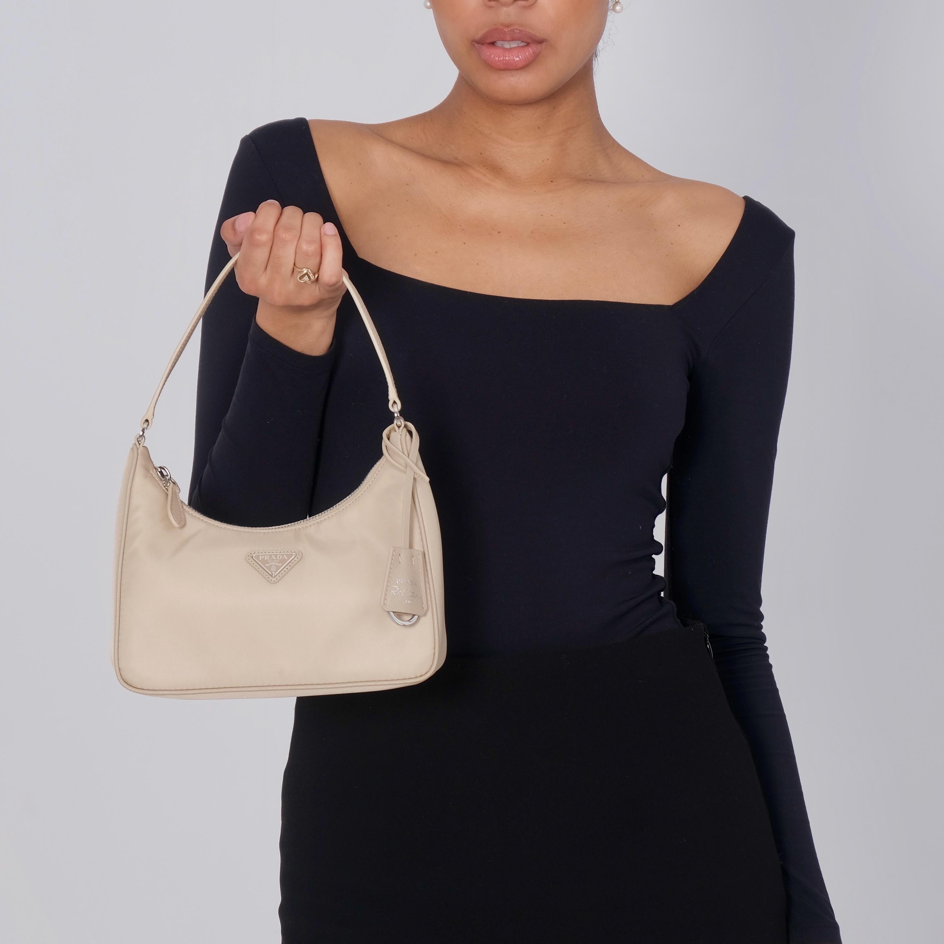 This Prada shoulder bag is made of sturdy beige tessuto nylon with silver hardware. The bag features a nylon shoulder strap and the top zipper opens to a beige jacquard fabric interior. Category, retail.

Authenticated by Real