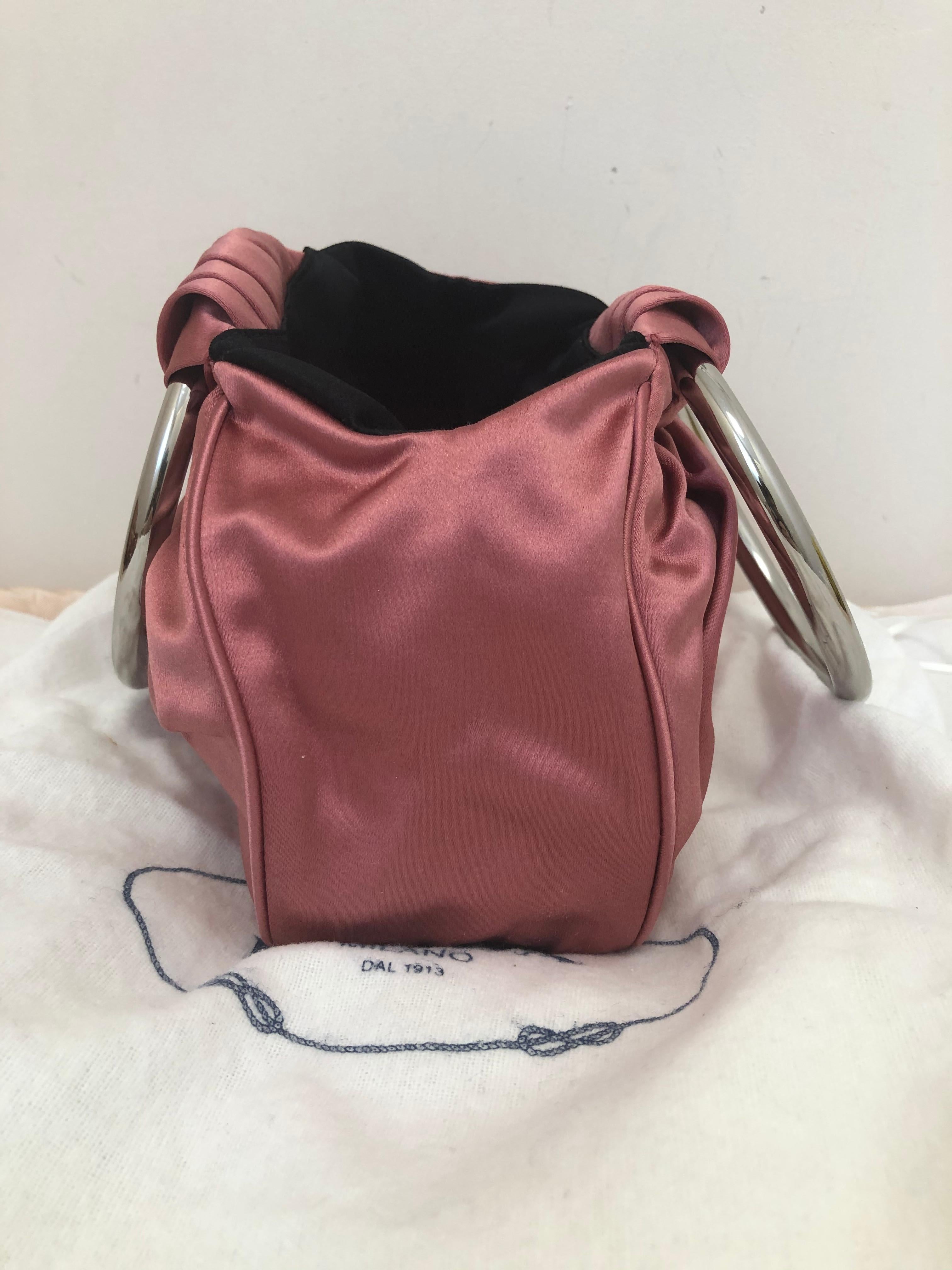 Such a cute lilac/pink bag, perfect for the evening, or as an accessory with a more informal outfit. It has oversized silver tone loop handles, which contrasts with the pleated satin body. There is the Prada logo plate to the front, and inscription