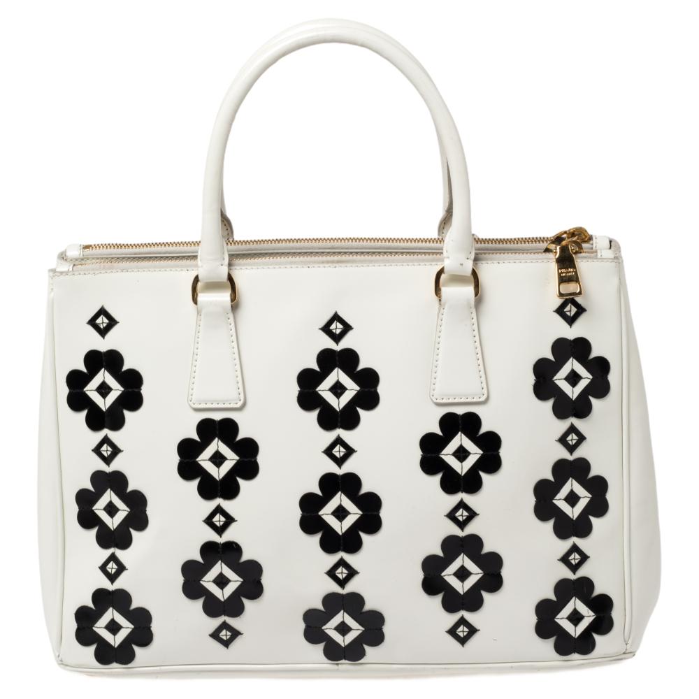 Femenino en su forma y grandioso en su diseño, este bolso tote con doble cremallera de Prada será una adoración en tu armario. Se ha confeccionado en polipiel y se ha decorado mínimamente con herrajes dorados. Viene con dos asas superiores, dos