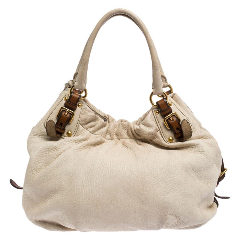 Made with love, this exclusive bag is from the house of Prada. This satchel has been crafted in Italy and is made from quality leather. It comes ina stunning shade of off-white. It is held by dual-rolled handles with buckle detailing, features a