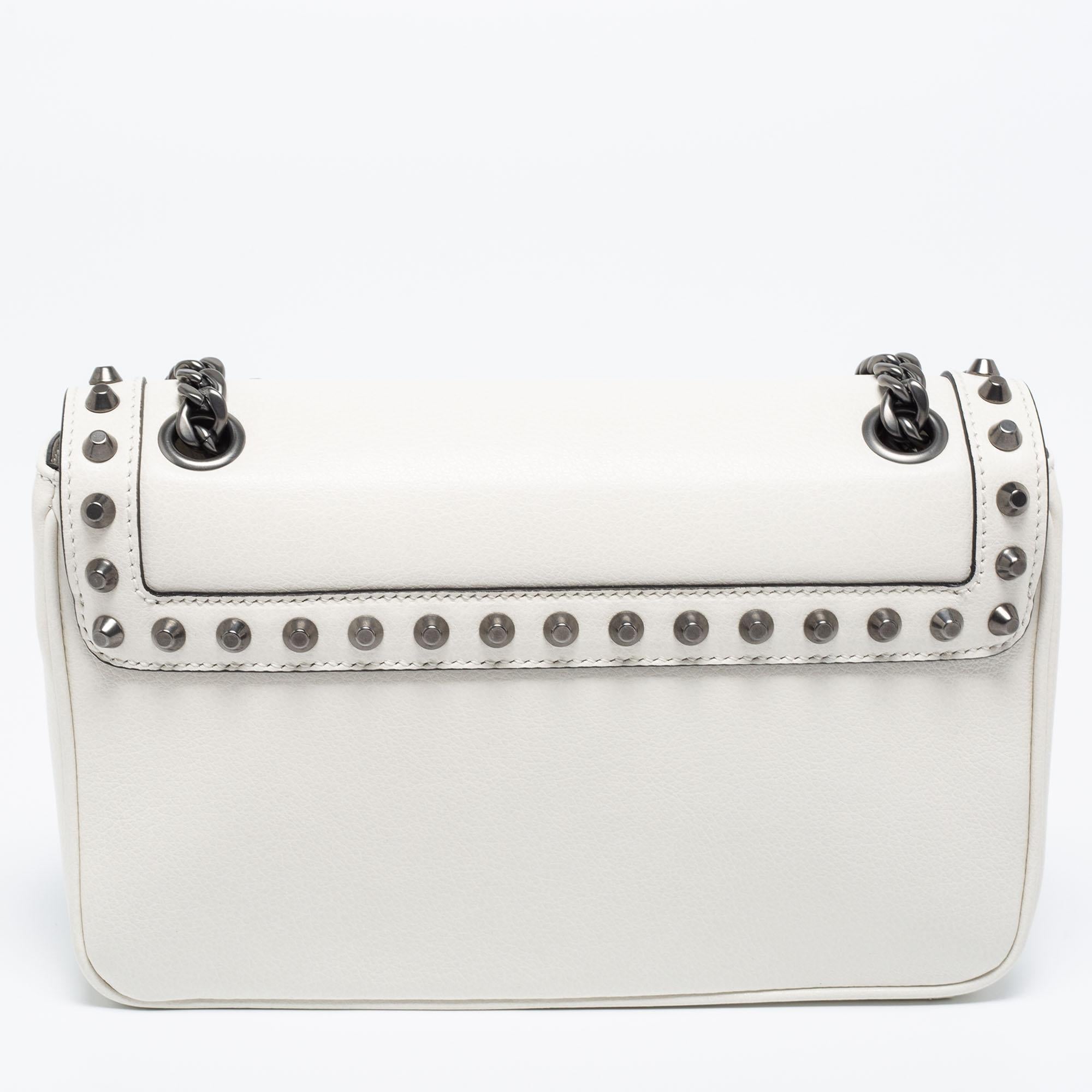 Experience fine craftsmanship with this immaculately-designed bag by Prada. It is crafted using off-white leather, which is highlighted with studded embellishments. It features a 55 cm shoulder strap, gunmetal-tone hardware, and a neat nylon-lined
