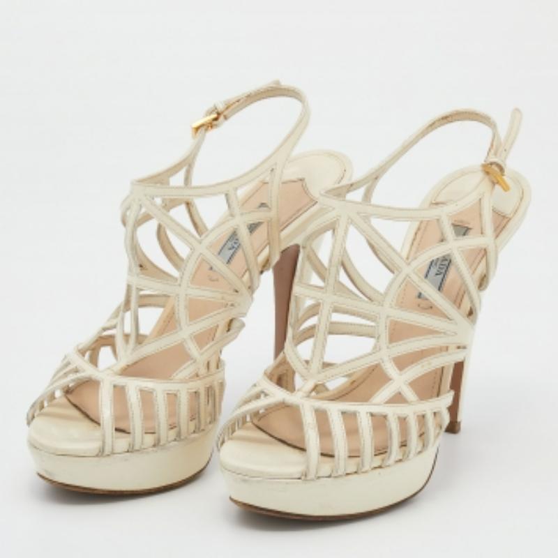 Sehen Sie umwerfend aus in diesen luxuriösen Sandalen von Prada. Die Sandalen sind aus Lackleder gefertigt und verfügen über ein Plateau, einen Knöchelriemen mit Schnalle und einen 13 cm hohen Absatz. Die Silhouette dieses Paares mit Käfig umrahmt